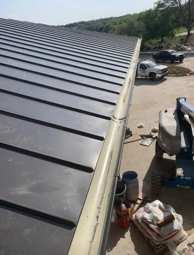 Standing seam panel and gutter detail on a metal roofing jobsite in Gatesville